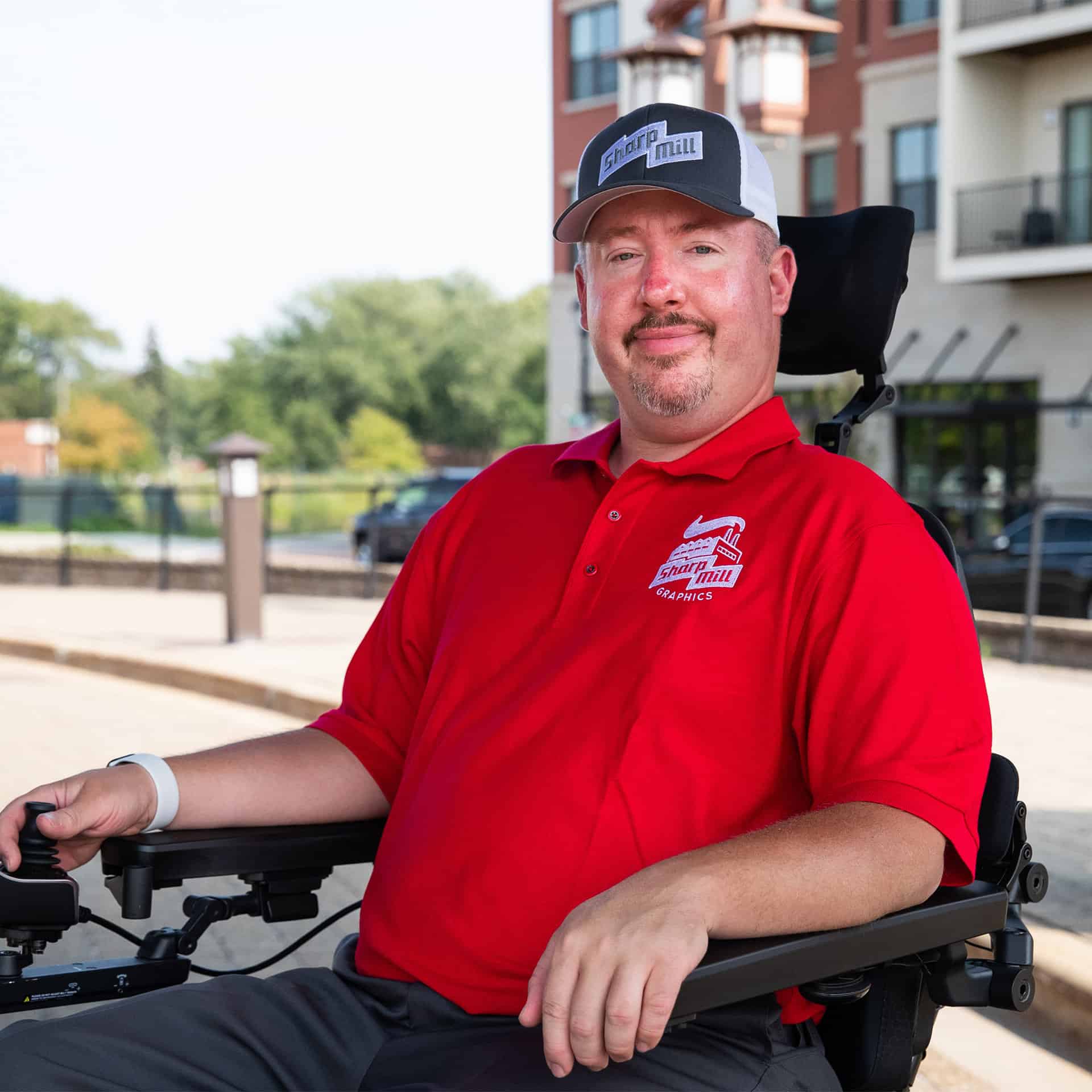 A man in a red shirt sitting in a wheelchair.