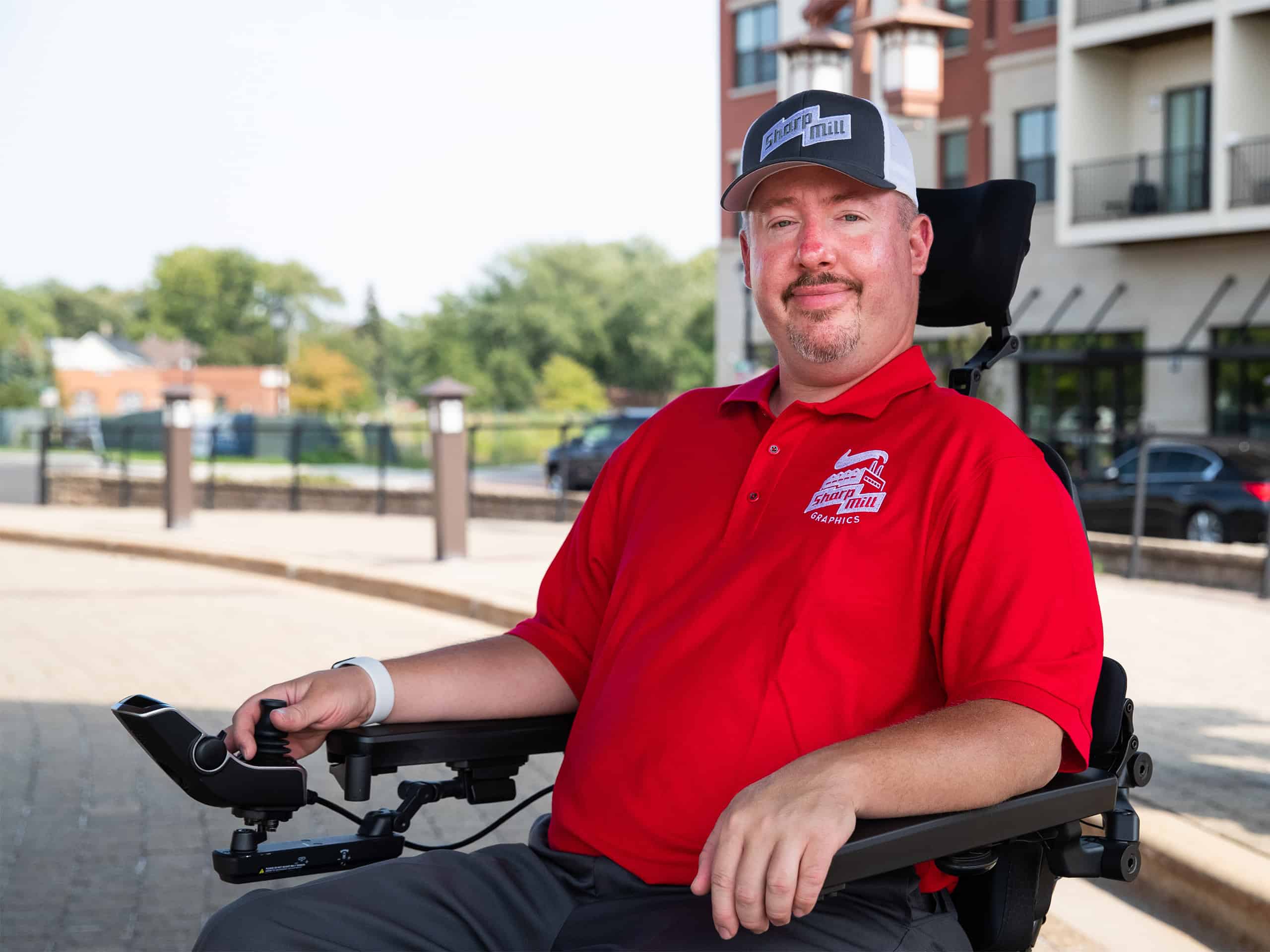 A man in a red shirt sitting in a wheel chair.