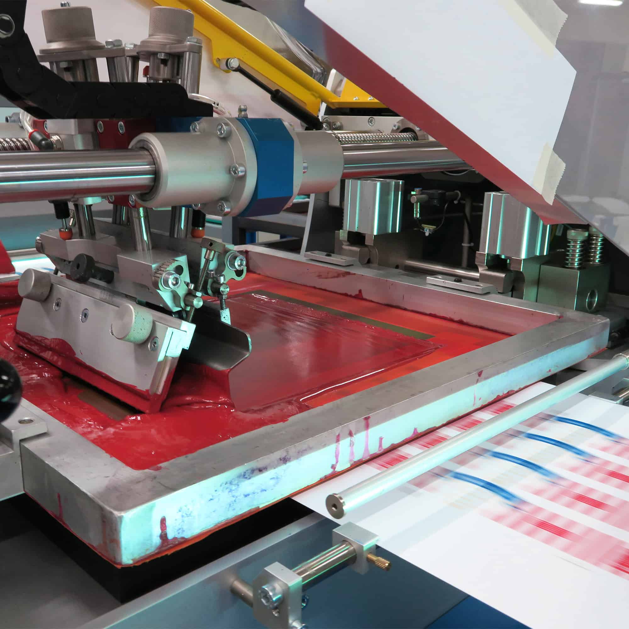 A machine is cutting a red sheet of paper.