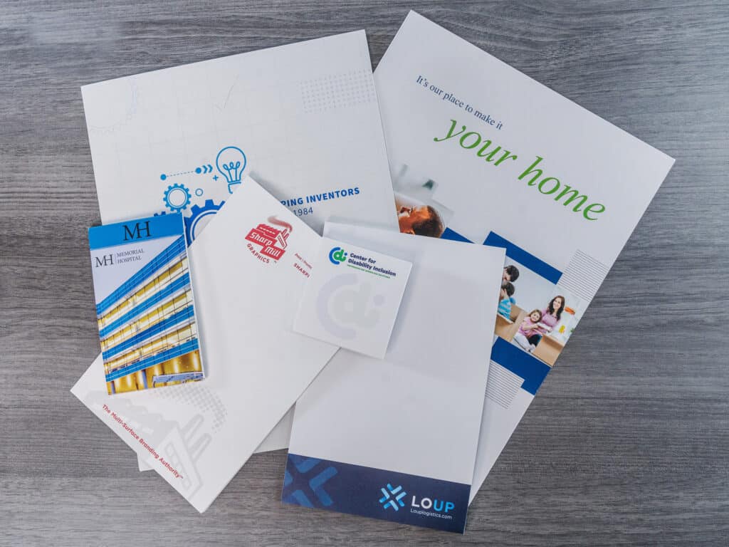 A set of printed marketing materials, including business cards and envelopes, are neatly arranged on a table.